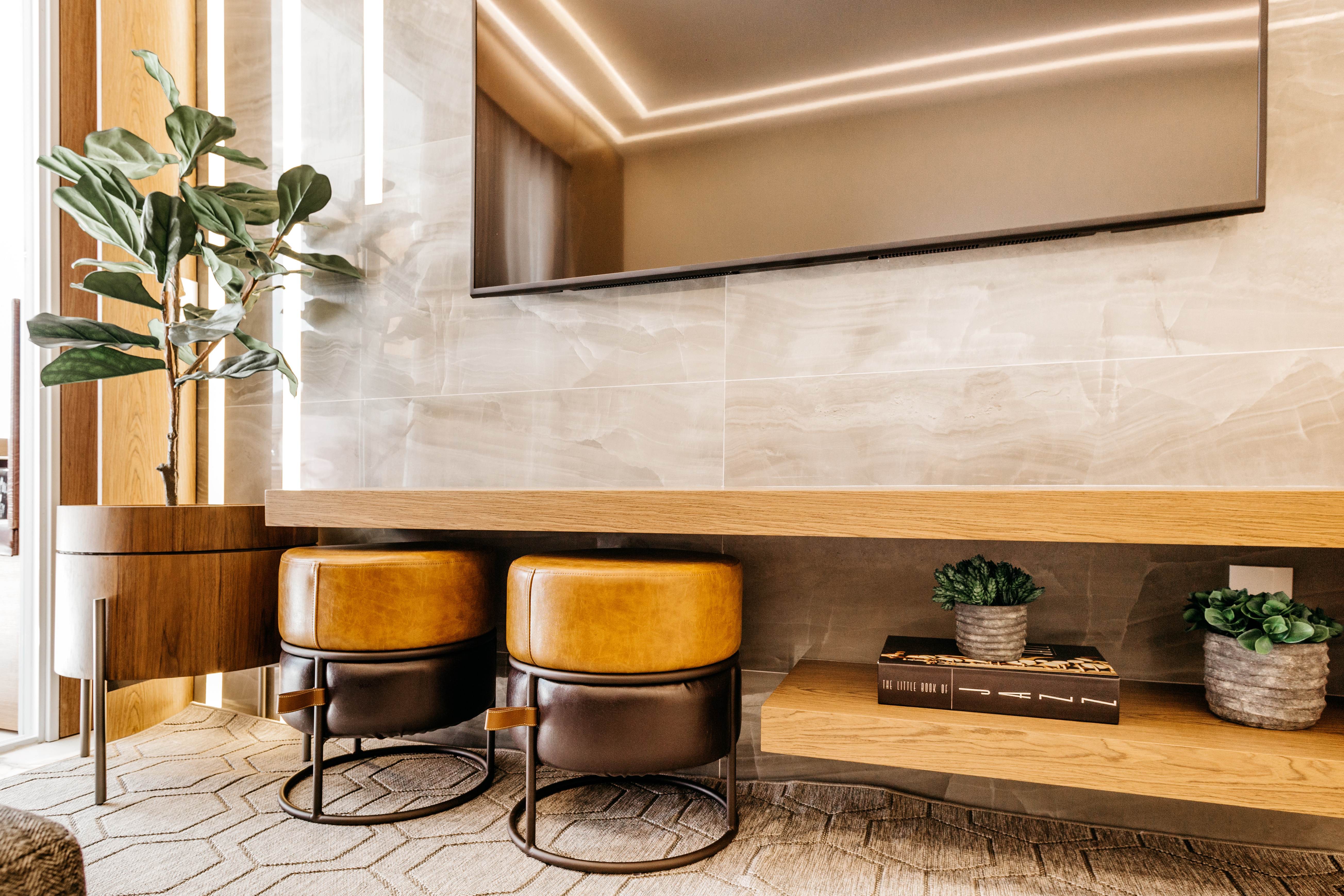 Hall com parede revestida em mármore claro, banquetas e nichos de madeira